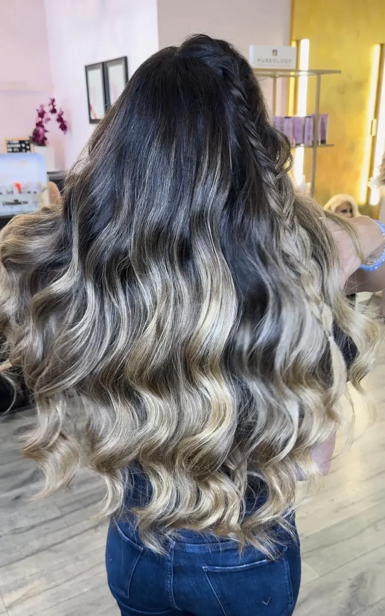 Romantic bridal hairstyle with soft waves and side braid in blonde ombré tones.
