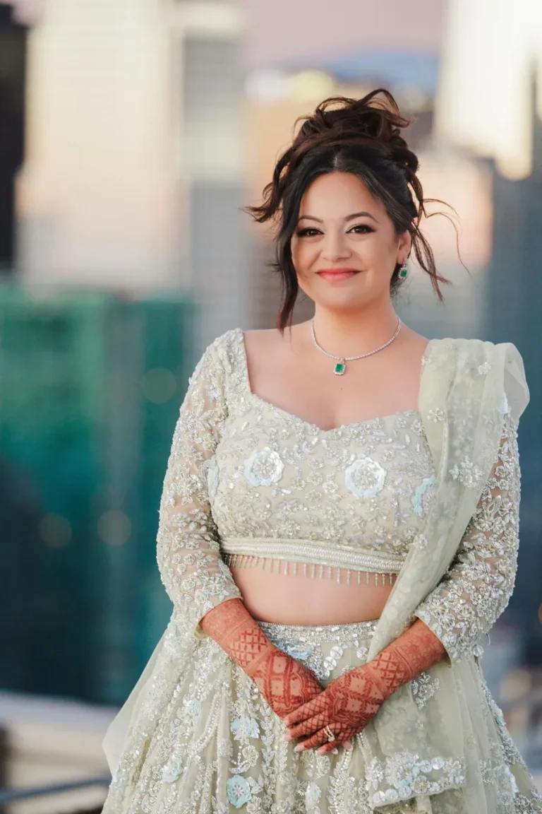 Smiling bride in a traditional embroidered lehenga with henna decorated hands